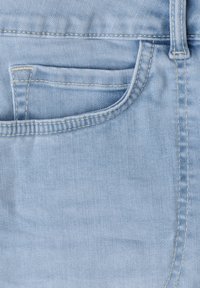 Tissu en denim bleu clair montrant la poche avant, la poche pour pièces, la boucle de ceinture et les détails de couture du jean.