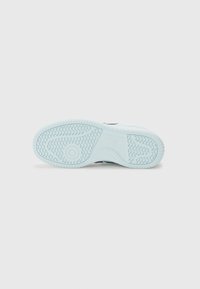 Semelle de sneaker en caoutchouc bleu clair avec un motif de semelle texturé, présentant des crêtes et des accents de design circulaires sur une surface lisse.