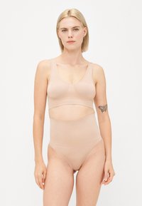 Naadloze huidkleurige beha en high-waisted slip set. Zachte, rekbare stof met een gladde textuur. Eenvoudig ontwerp, geen patronen of versieringen.