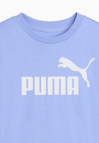 Ανοιχτό μωβ κοντομάνικο με στρογγυλή λαιμόκοψη, μεγάλο λευκό λογότυπο Puma και γραφικό με μια αλματώδη πάνθηρα στο στήθος.