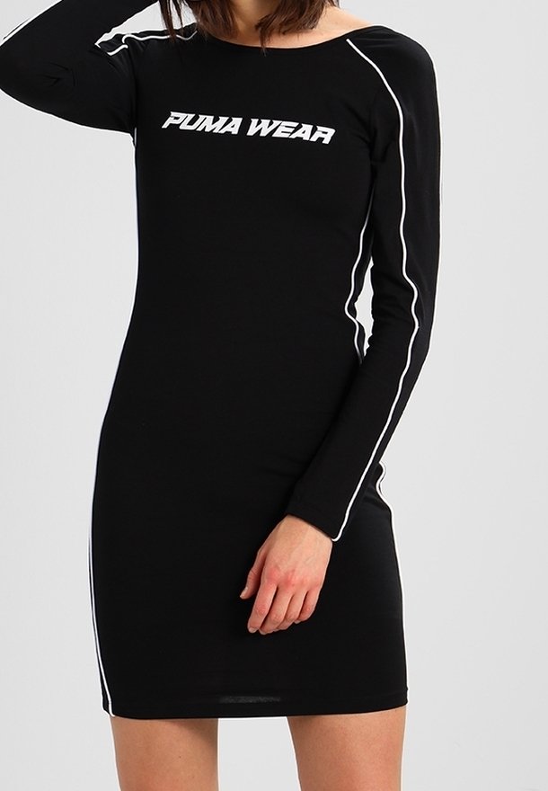 Femme portant une robe noire ajustée à manches longues avec un liseré blanc et le texte "PUMA WEAR" sur la poitrine.