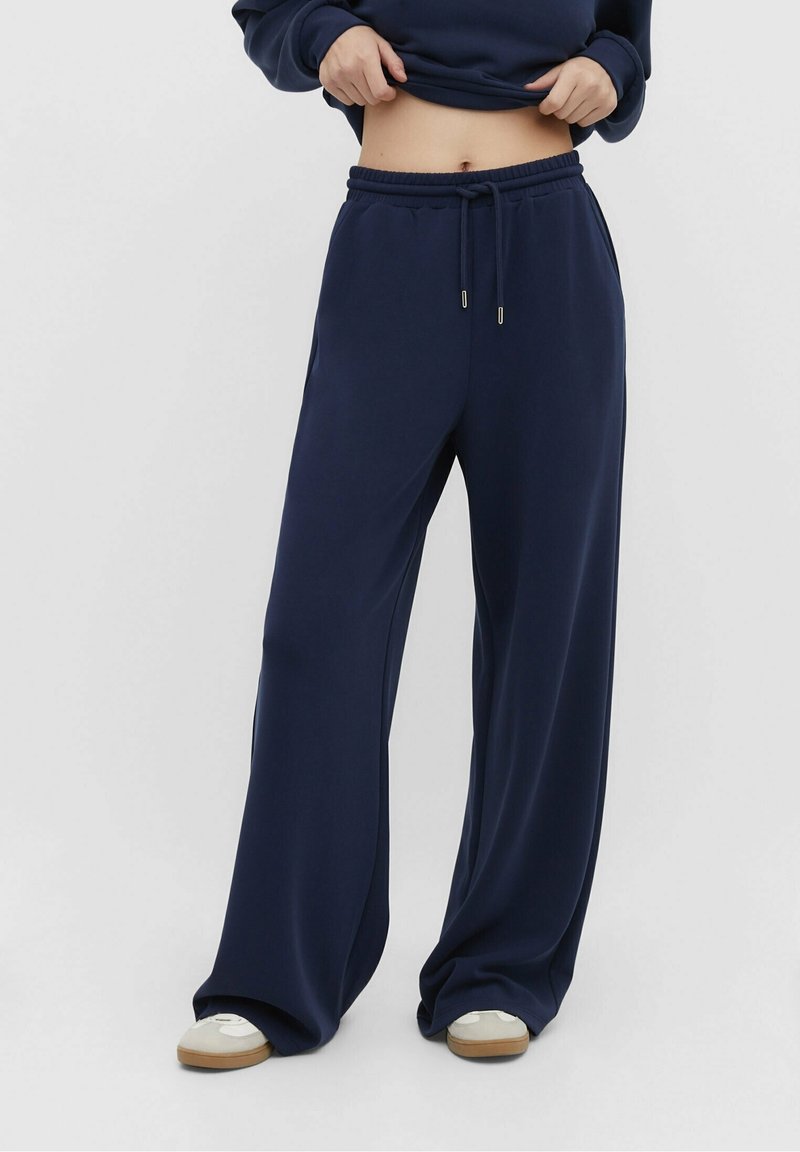 Marineblauwe wijde sweatpants met een elastische tailleband, trekkoord en zijzakken, gemaakt van een zachte, lichte stof.