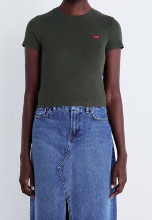 Olivgrünes, geripptes T-Shirt mit kurzen Ärmeln und kleinem rotem Logo, kombiniert mit einem blauen Jeansrock mit Frontriss und verwaschener Textur.