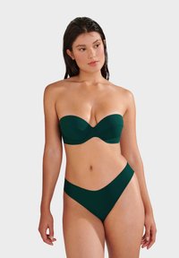 Strapless dark green bikini top with structured cups and seam detailing; matching high-waisted bottom with a smooth texture and minimalist design.