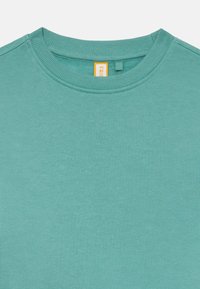 Felpa azzurro chiaro con collo a giro, dotata di un collo a costine e una texture morbida, con dettagli di cucitura minimi. Etichetta visibile sul colletto.