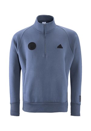 Blauer Fleece-Pullover mit einem Viertelreißverschluss, gerippten Bündchen und Saum. Mit einem schwarzen Logopatch und dem Text "EIN LEHR." Akzent auf dem linken Ärmel.