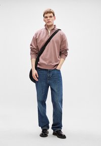 Světle fialová mikina na zip, modré džíny, černá taška a černé boty. Pohodlný střih s žebrovanými manžetami a lemem. Jednoduchý design, bez vzorů.