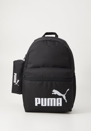 Černý látkový batoh s přední zipovou kapsou, na které je velké bílé logo "PUMA" a silueta běžící pumy. Obsahuje také boční kapsu.