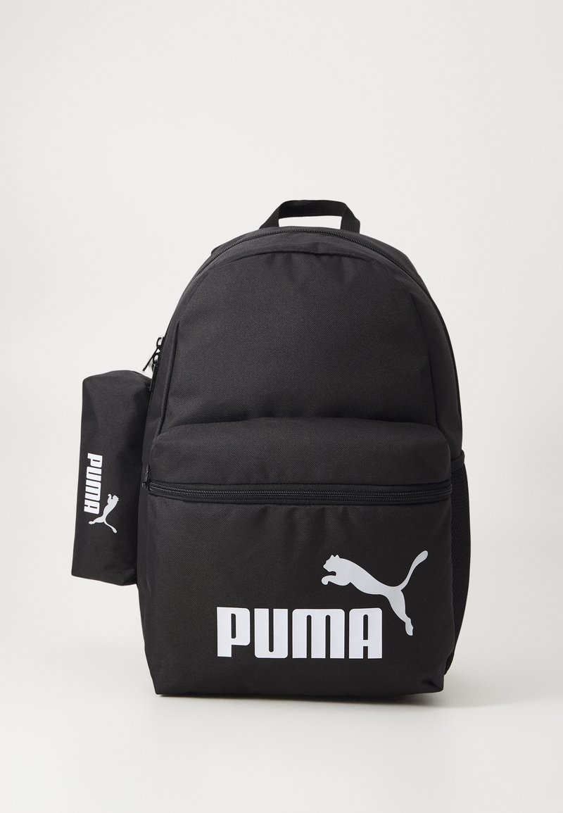 Svart stoffryggsekk med en frontlomme med glidelås, og stor hvit "PUMA"-logo samt silhuett av en løpende puma. Inkluderer en sidelomme.