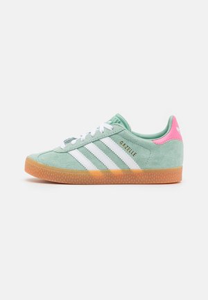 Mint green Adidas Gazelle sneaker with white stripes, gum sole, and pink heel tab, shown from the outer side on white background.