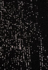 Svart tyg täckt med spridda silverpaljetter med en strukturerad yta, vilket skapar en glänsande effekt över materialet.