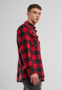 Rot-schwarz kariertes Flanellhemd mit langen Ärmeln, zwei Brusttaschen und Manschetten mit Knöpfen; weiche Textur und lässige Passform.