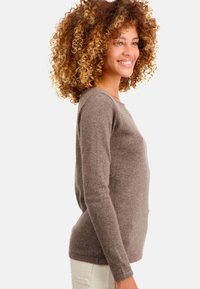 Pull en tricot doux de couleur brun, avec un col rond et des manches longues, à la silhouette ajustée et au design minimaliste.