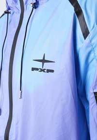 Giacca azzurra chiara con zip nera, coulisse nera e logo "PXP" nero con stella sul petto.