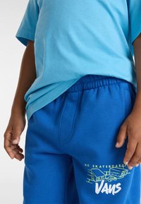 Lichtblauw katoenen T-shirt gecombineerd met felblauwe joggingsbroek met een elastische tailleband en een groene grafische print op het onderbeen.