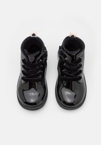 Černé kotníkové lesklé boty z lakované kůže se šněrováním vepředu, bočním zipem a srdíčkovým ozdobným prvkem na patě. Hladký, lesklý povrch.