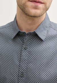 Katoenen shirt in donkerblauw met een klein wit ruitpatroon. Heeft een button-down kraag en knopen aan de voorkant, met een gladde textuur.