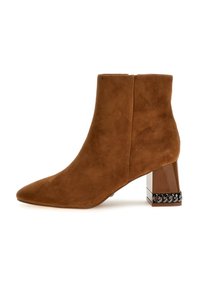 Stivale alla caviglia in suede marrone con punta affusolata e tacco largo, caratterizzato da una base marrone lucida e un accento di catena nera attorno al tacco.