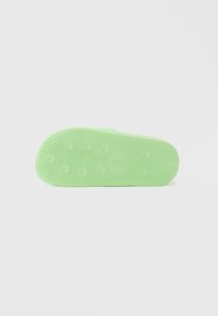 Green rubber shoe sole featuring a textured pattern with circular grip points and a smooth edge.