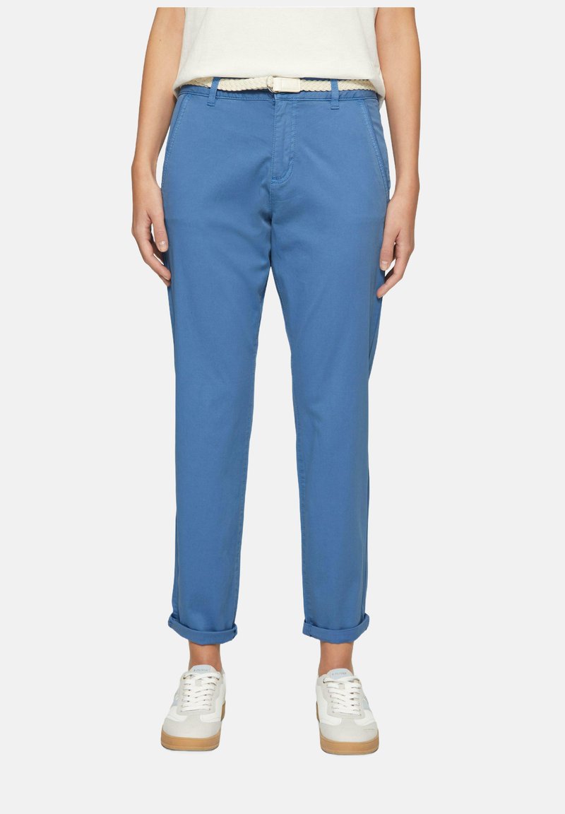 Lichtblauwe katoenen broek met opgerolde manchetten, voorzien van zijzakken en een beige geweven riem, gecombineerd met witte sneakers.