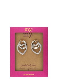 Srebrne kolczyki w kształcie serca z połyskującym wykończeniem i ozdobione przezroczystymi kryształami, zaprezentowane w różowym pudełku na kartę.