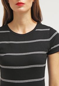 Zwarte top met korte mouwen en horizontale witte strepen. Zachte, rekbare stof; ronde halslijn; aansluitend ontwerp, geschikt voor casual wear.