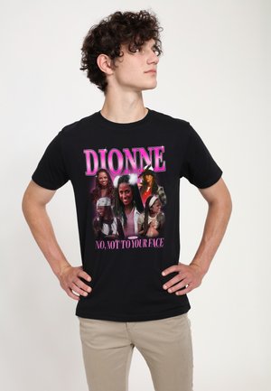 Junger Mann mit lockigem Haar trägt ein schwarzes T-Shirt mit mehreren Fotos einer Frau und dem Text „DIONNE“ und „NEIN, NICHT INS GESICHT".