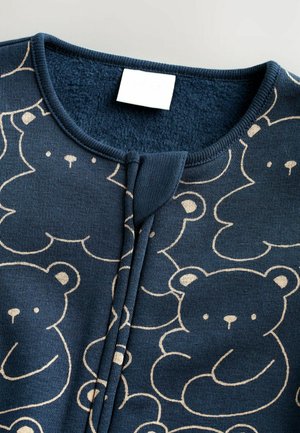 Donkerblauwe katoenen kledingstuk met een herhalend lichtbeige berenpatroon, voorzien van een ronde hals, een textuurafwerking en een voorste drukknoopsluiting.