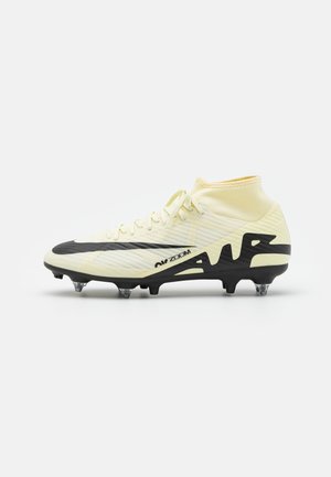 Chaussure de football synthétique jaune avec un col haut, un dessus texturé, des accents noirs et trois crampons transparents pour l'adhérence.