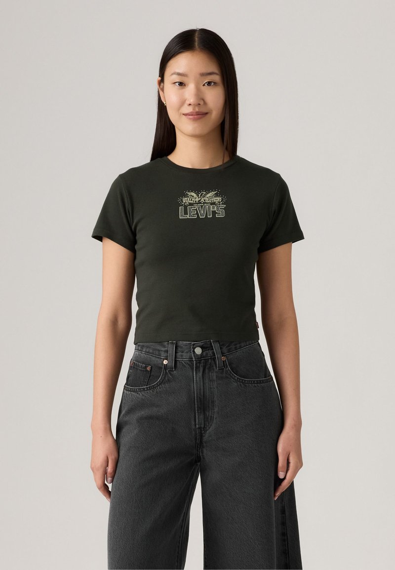 T-shirt court vert foncé à manches courtes, avec un motif "Levi's" en couleurs plus claires. Associé à un jean en denim noir taille haute.