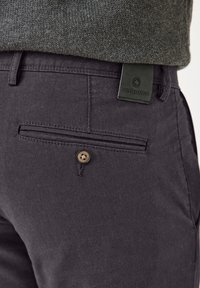 Dunkelgraue Chinos aus strukturiertem Stoff, mit einer Gesäßtasche, die einen braunen Knopf und ein schwarzes Lederetikett mit der Aufschrift „redpoint" trägt.