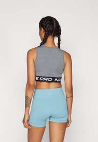 Szürke sportmelltartó fekete "NIKE PRO" csíkkal és világoskék, magas derékú rövidnadrággal, sima textúrával és testhezálló fazonnal.