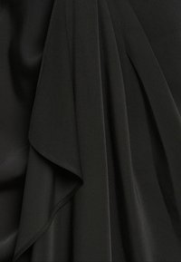 Tela negra que muestra una textura suave y fluida con capas drapeadas. El material tiene un acabado liso y un brillo sutil, acentuando los pliegues.