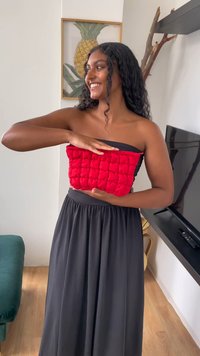 Rød polstret crop-top med quiltet design holdt foran et svart skjørt. Har en stroppeløs utringning og teksturert stoff.