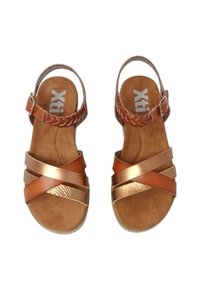 Sandali in pelle marrone con suole piatte, dotati di ampie cinghie incrociate in bronzo metallico e una cinghia alla caviglia intrecciata. Logo sulla soletta.