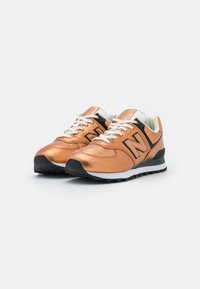 Zapatillas de cuero bronce con cordones blancos, detalles en negro y una superficie texturizada. Cuentan con una suela acolchada y un logo en el lateral.