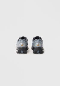 Baskets de sport grises avec un dessus texturé, des détails en mesh et un motif distinctif. Semelle noire avec un amorti, arborant un logo air au talon.