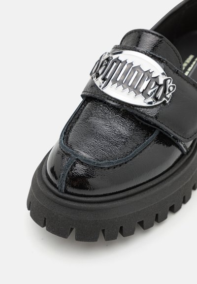 Mocassino in pelle verniciata nera con un evidente dettaglio del logo argento, suola in gomma spessa e strutturata, e cuciture decorative vicino alla punta.