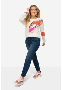 Bílý svetr s barevným potiskem humra na jedné rukávě, spárovaný s tmavě modrými džíny a teniskami s růžovými akcenty. Hladká textura, ležérní design.