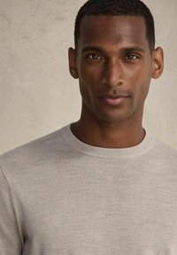 Ljusgrå crewneck-tröja i mjukt stickat tyg, med slät yta och ribbat detaljer runt halsringningen.