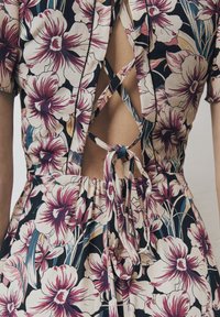 Vestido floral de tela ligera en azul marino con flores blancas y burdeos. Presenta un espalda cruzada y una cintura elástica con un lazo.