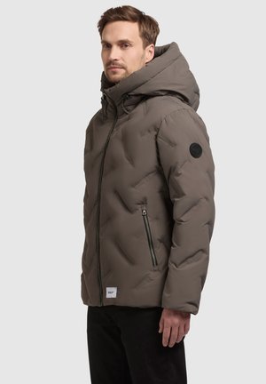 Gepolsterte, gefütterte Jacke in Olivgrün. Mit einem Reißverschluss, zwei seitlichen Reißverschlusstaschen und einem Markenpatch am linken Ärmel.