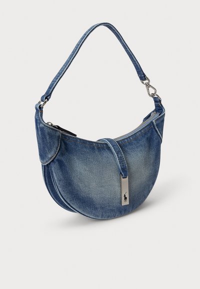 Íves formájú farmer válltáska kontrasztos varrással és ezüst logó díszítéssel. Egyetlen pánttal és cipzáras záródással rendelkezik.