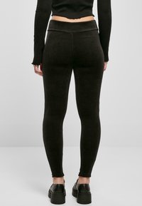 Czarne prążkowane legginsy z wysokim stanem i dopasowanym krojem. Subtelny detal teksturowy, rozszerzane mankiety, w połączeniu z masywnymi czarnymi butami.