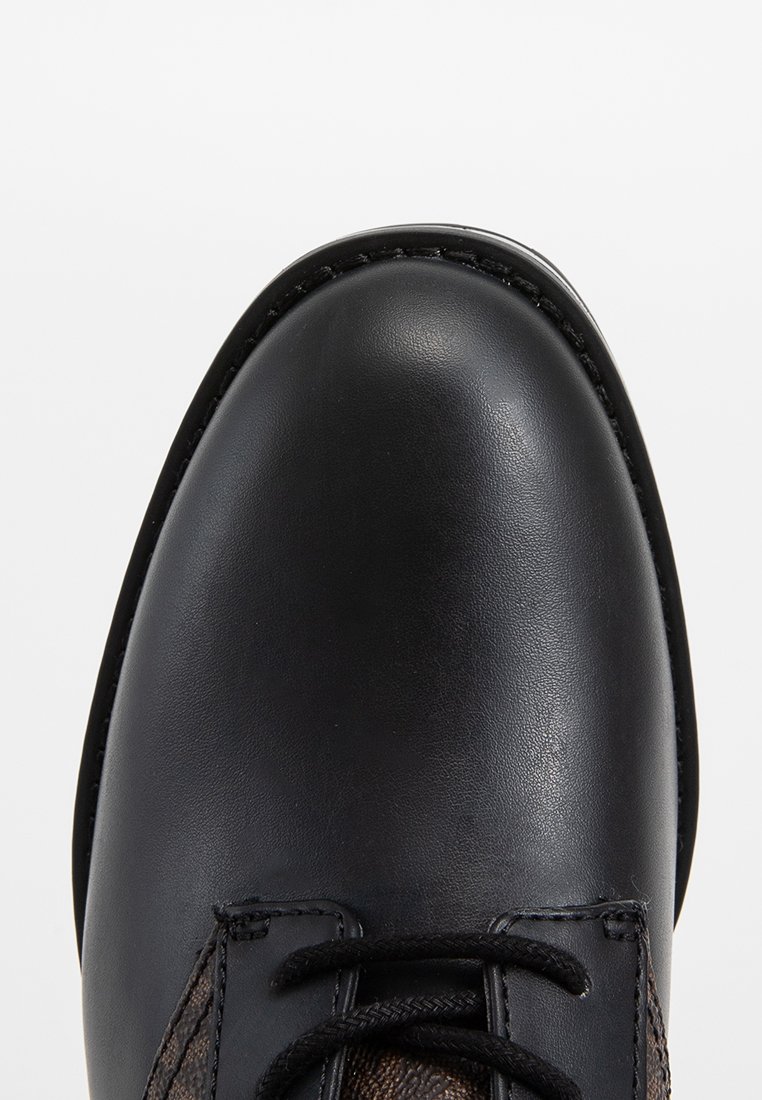 Zwarte leren dresschoenen met een ronde neus, textuur bruin stoffen panelen aan de zijkanten en contrasterende zwarte stiksels langs de zool.