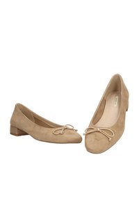 Bailarinas de ante beige con puntera redondeada, pequeño tacón cuadrado y un lazo decorativo en la parte frontal. Textura suave y diseño sencillo.