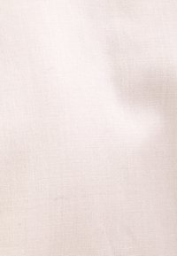 Tissu texturé beige clair avec un fin motif côtelé horizontal et de légers plis naturels.