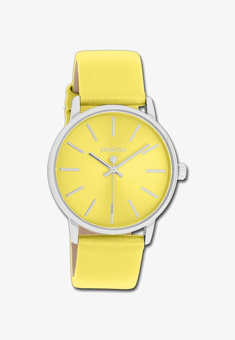 Montre ronde jaune avec une finition mate, marqueurs d'heures et aiguilles en argent. Bracelet en silicone jaune doux, quincaillerie en argent poli.