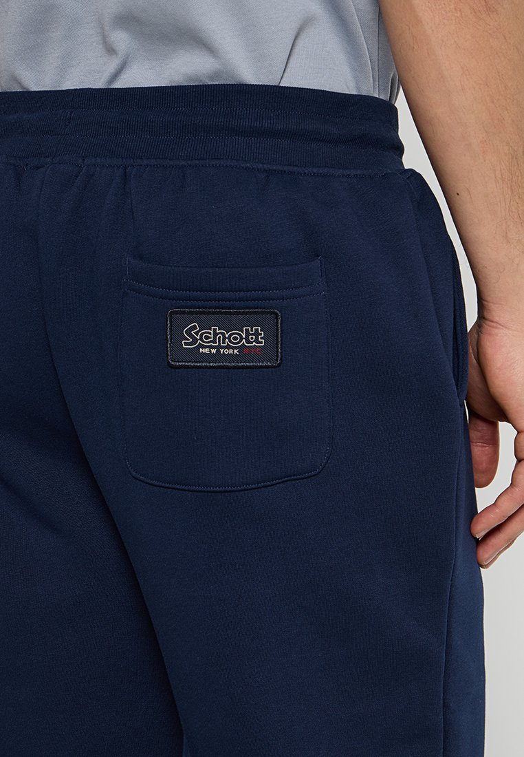 Pantaloni sportivi navy con tasca posteriore, caratterizzati da un'etichetta rettangolare Schott New York. Realizzati in tessuto morbido con una texture liscia.