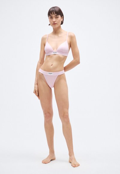 Világos rózsaszín bikiniszett háromszög alakú melltartóval, vékony pántokkal és hozzáillő tanga alsóval, mindkettőnél logós szalag a derékrészen.